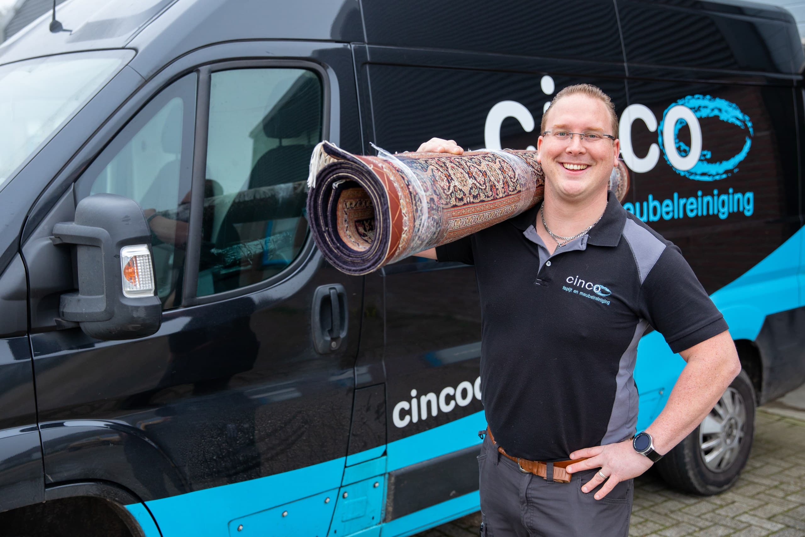 Medewerker met een opgerold vloerkleed bij de bus