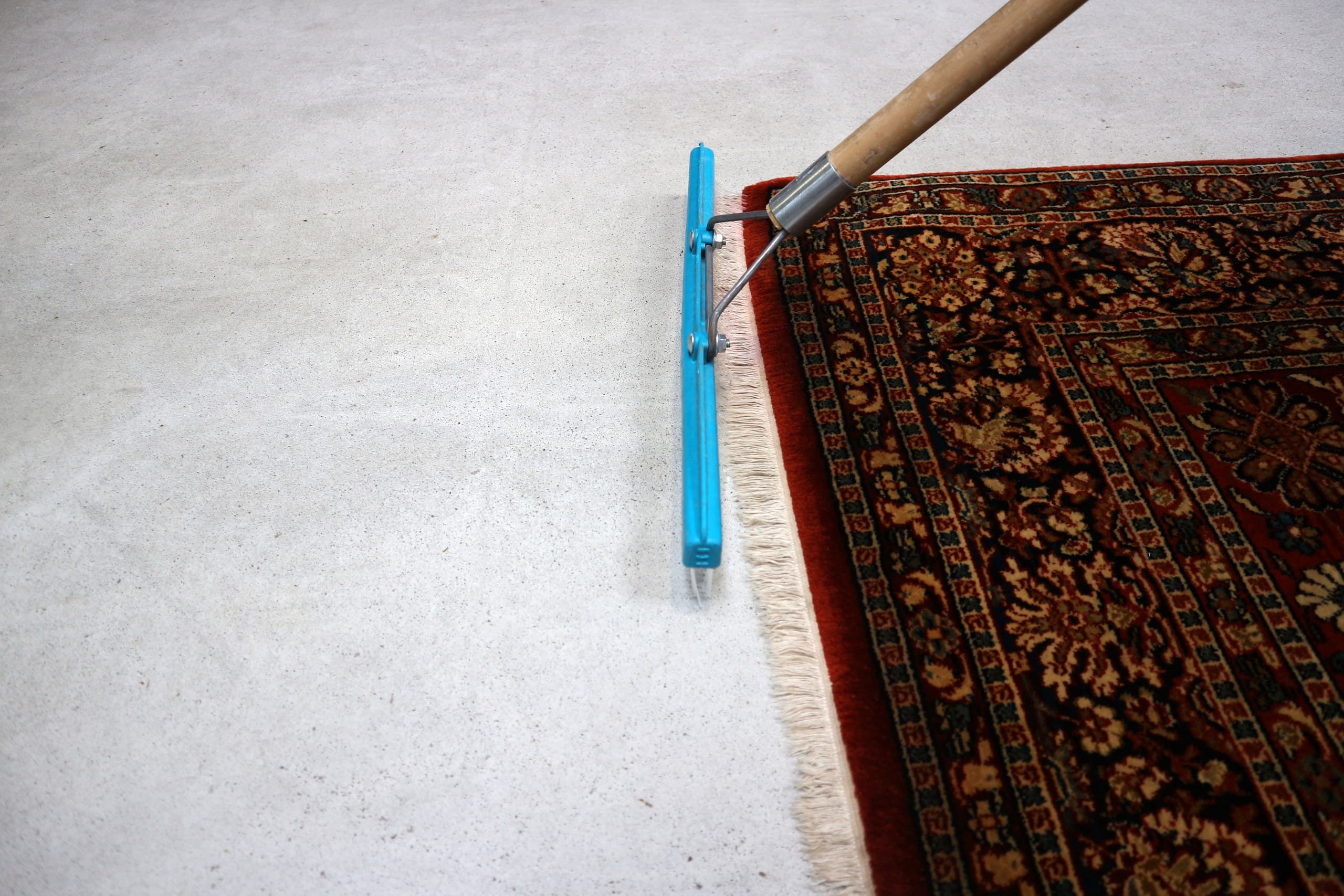 Vloerkleed met franjes wordt met een borstel behandeld in de wasserij