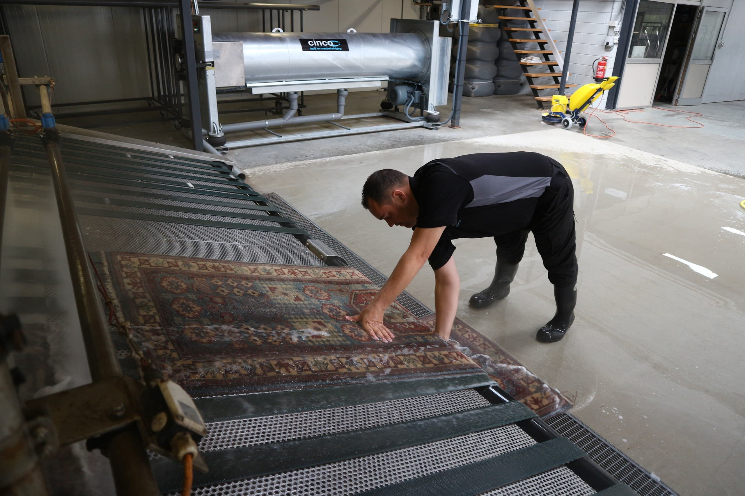 Medewerker wast met de hand een vlakgeweven vloerkleed in de wasstraat