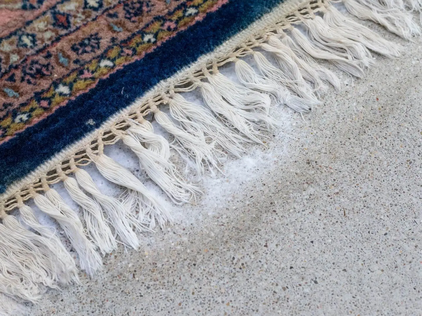 Close-up van de witte franjes van een Perzisch Nain vloerkleed tijdens de reiniging