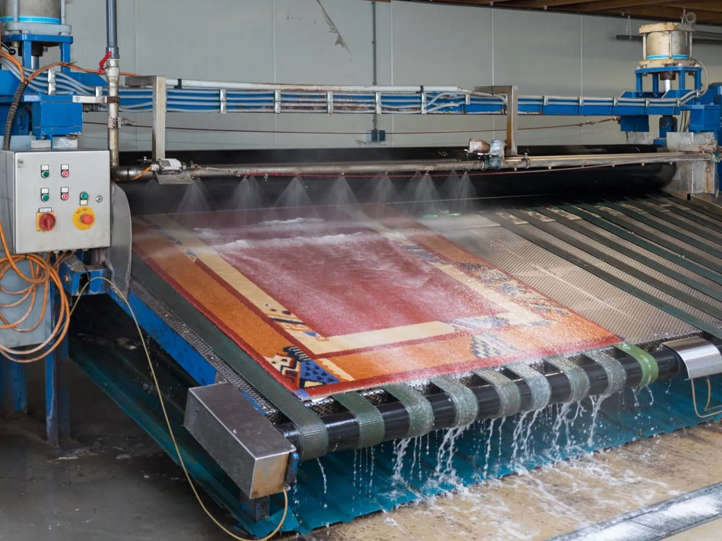 Rood oosters kleed wordt gespoeld op de spoelmachine onder de sproeiers