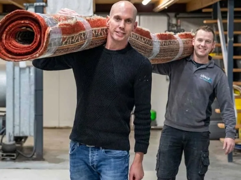 Willem en Albert Blok dragen een gereinigd vloerkleed in de wasserij van Kleda