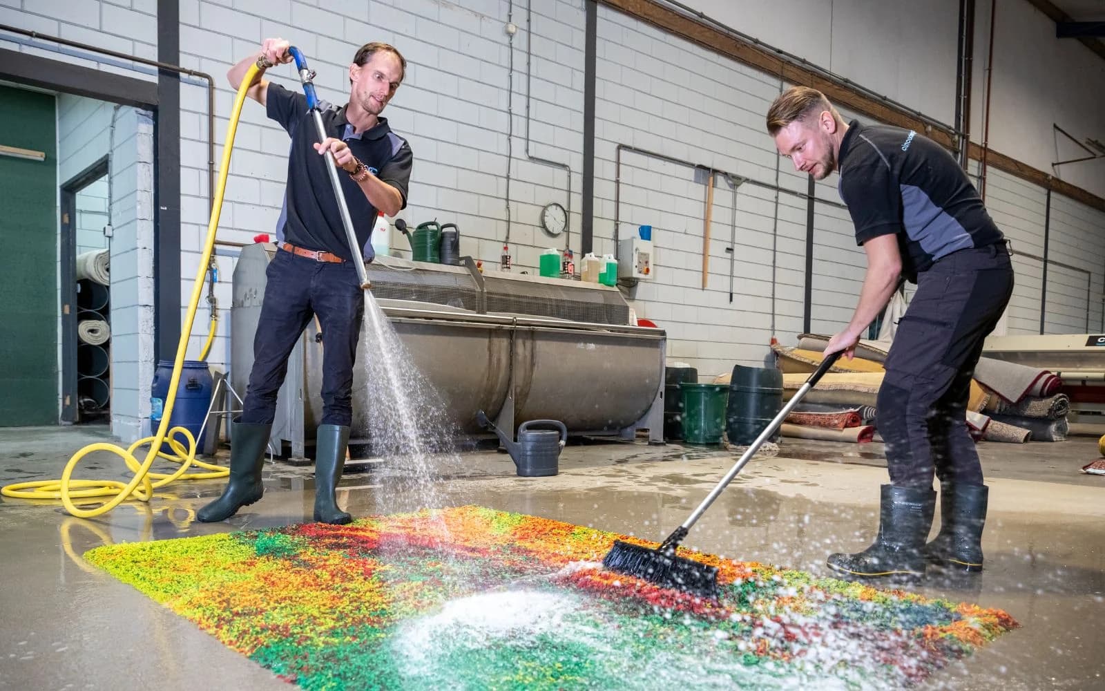 Kleda medewerkers reinigen vakkundig een kleurrijk vloerkleed in de wasserij