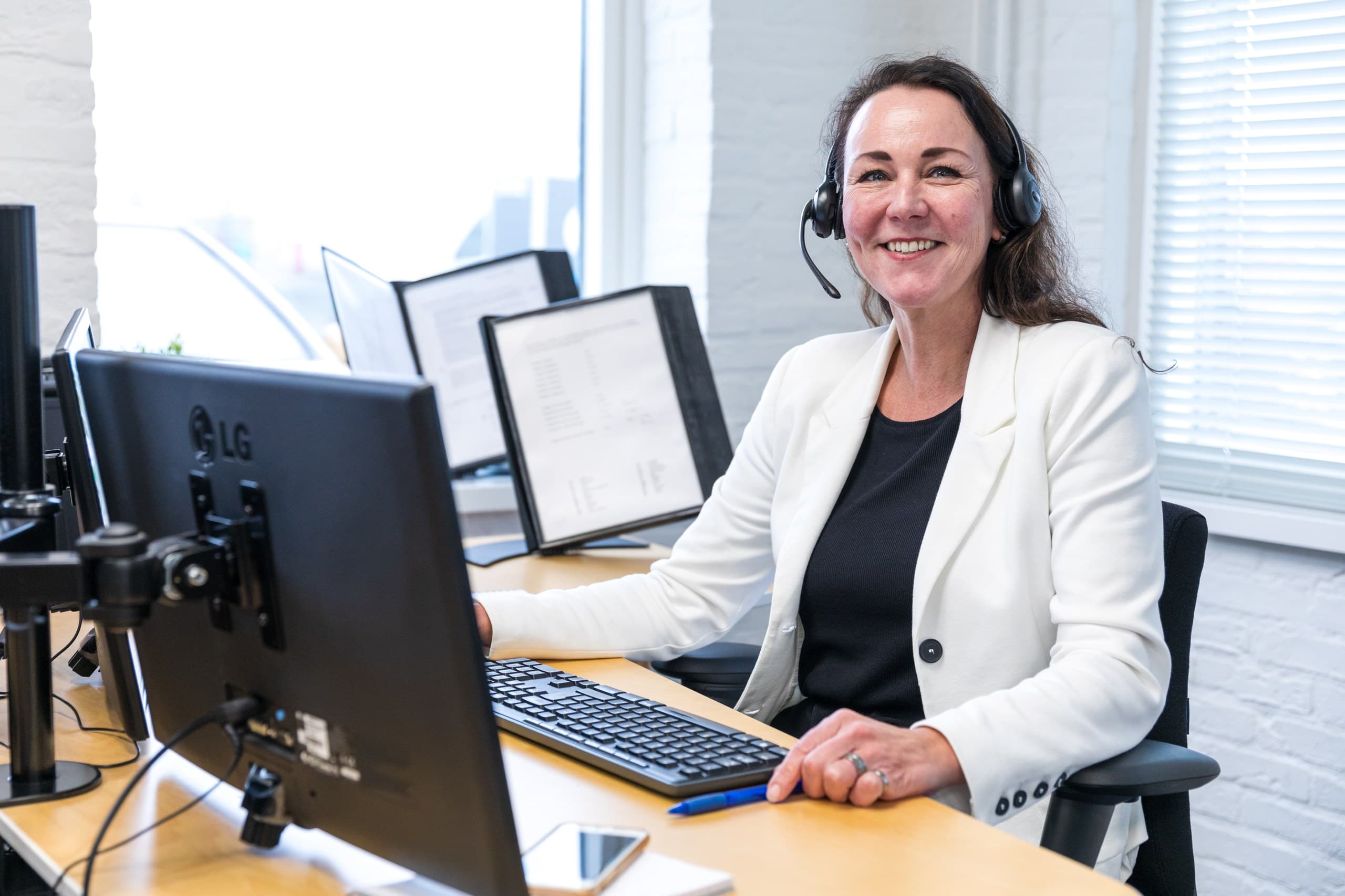 Medewerker van de klantenservice met headset achter het bureau