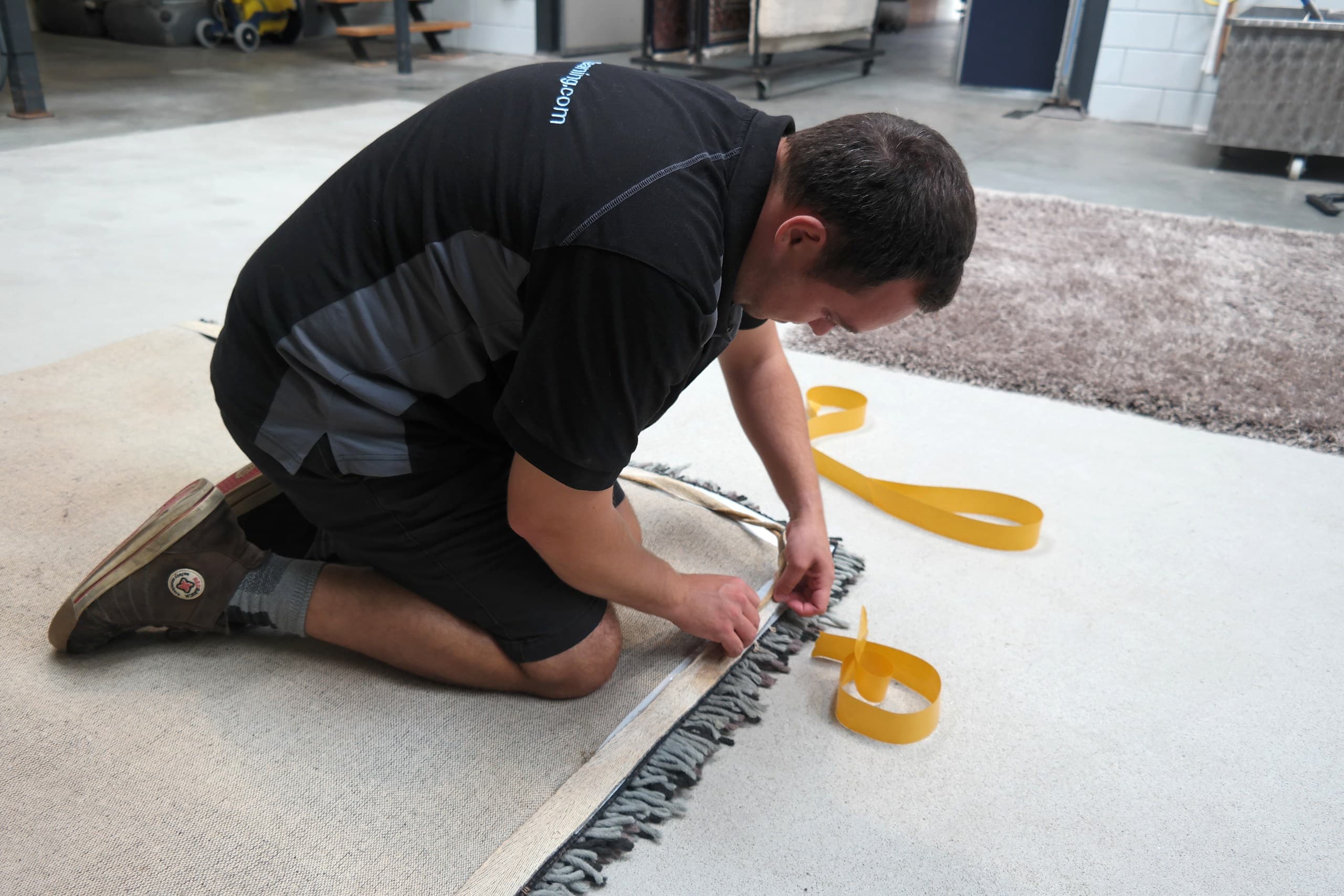 Medewerker inspecteert de franje van een vloerkleed in de wasserij