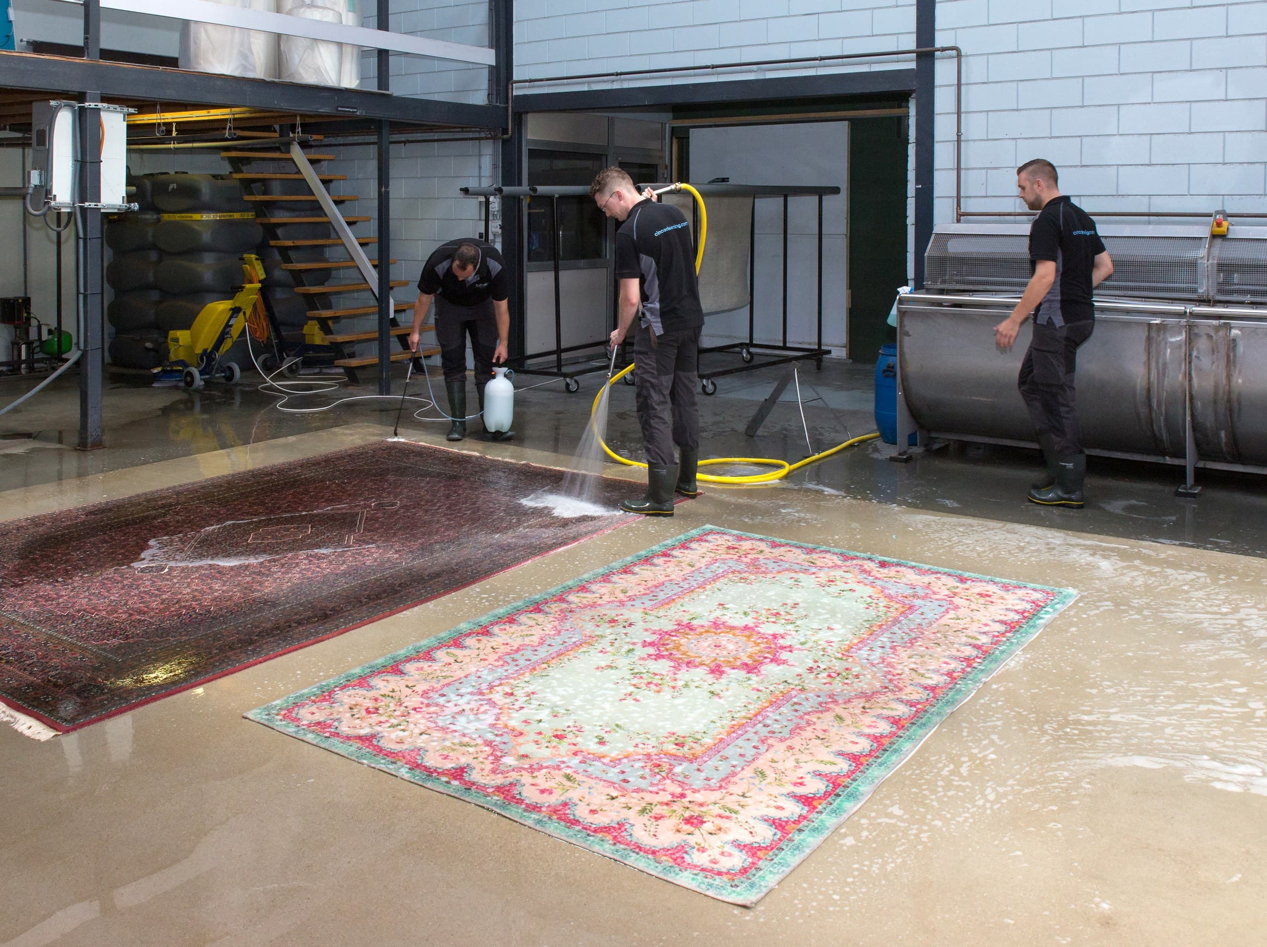 Medewerkers behandelen vloerkleden in de wasstraat