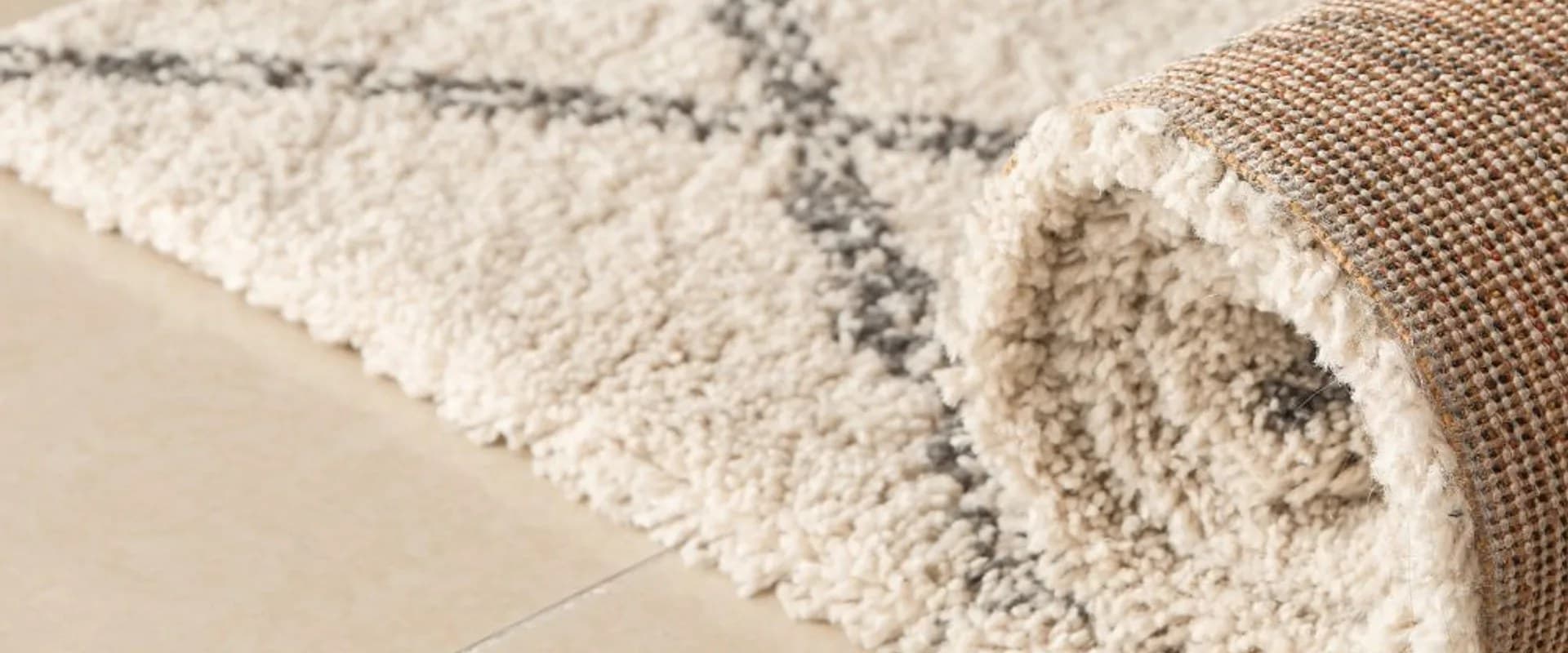 Opgerold hoogpolig creme berber vloerkleed met grijs ruitpatroon